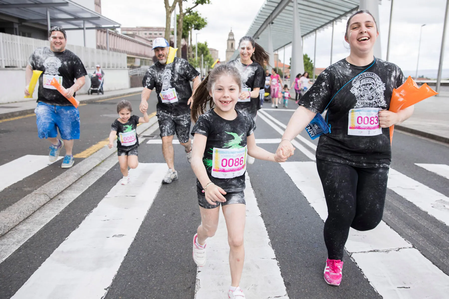 Persoas adultas e nenas participando xuntas nunha carreira popular inclusiva.